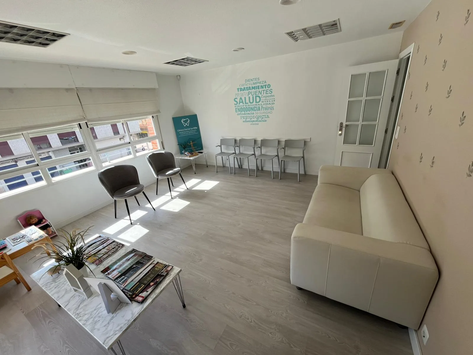 Sala de espera con sofá, expositores y el mural de la clínica al fondo